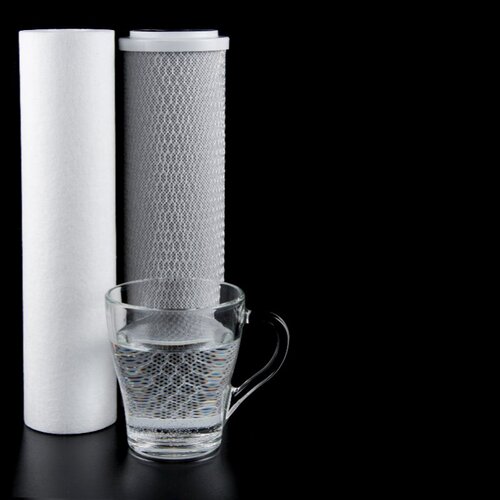 pair of carbon water filters next to a glass of clean water