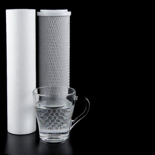 pair of carbon water filters next to a glass of clean water