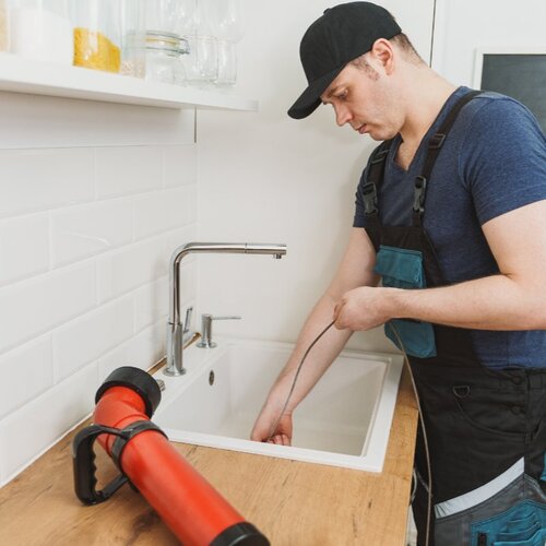 plumber clearing a kitchen drain