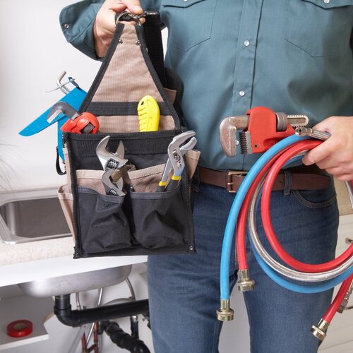 plumber holding plumbing tools and equipment