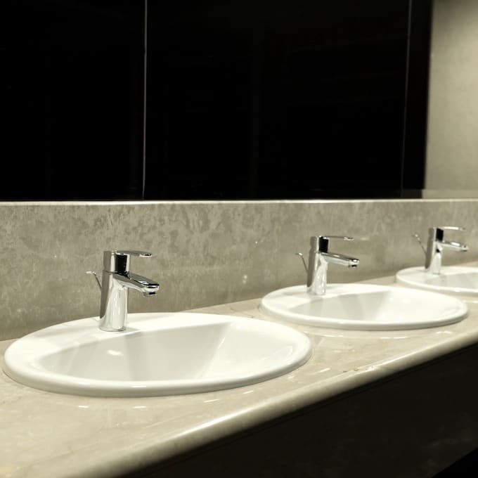 A line of freshly installed chrome faucets in a public bathroom
