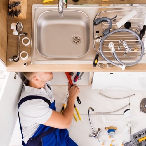 plumber under sink for repairs