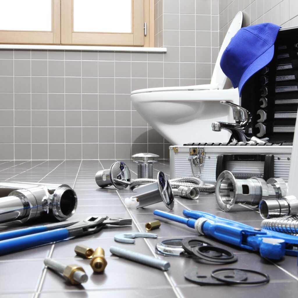 plumbing tools scattered on bathroom floor in front of toilet