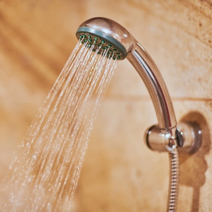 A chrome showerhead is streaming hot water into a bathtub.